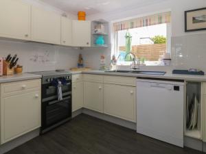 a kitchen with white cabinets and a black dishwasher at Wingelock in Rhosneigr