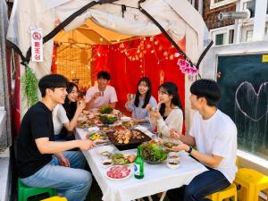 a group of people sitting around a table eating food at 20프로할인 대전역 단독주택 우송대 복층형하우스 숮불바베큐하우스 in Daejeon