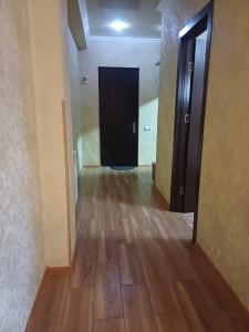 a hallway with a black door and a wooden floor at Your warm host in Kutaisi
