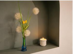 a vase with flowers and a candle on a table at Komfortowe Apartamenty i Pokoje Powidz in Powidz