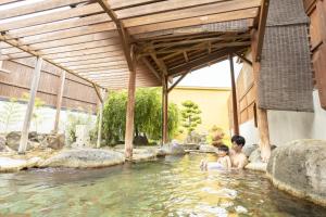 two people are sitting in a pool of water at Ooedo Onsen Monogatari Ureshinokan in Ureshino