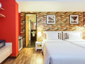 a bedroom with two beds and a brick wall at ibis Styles Chiang Mai in Chiang Mai