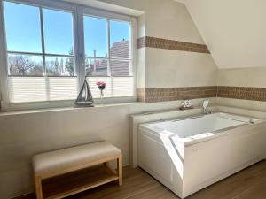 a large white tub in a bathroom with windows at Ferienhaus Sundevit - exklusives Ferienhaus mit Infrarotsauna, Whirlpool-Wanne und Kamin in Putgarten