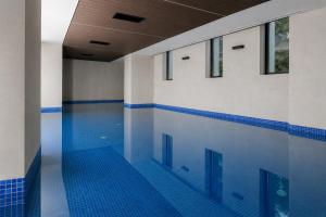 an empty swimming pool with blue tile floors and windows at Hedonist Wellness & Spa in Zlatibor
