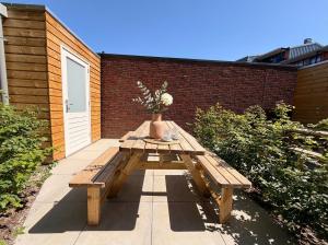 a wooden picnic table with a vase of flowers on it at Unique home near Tilburg center, uni & Efteling, in Tilburg