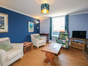 a living room with chairs and a tv and a table at The Old School House in Chichester