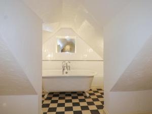 a bathroom with a white tub and a checkered floor at The Old School House in Chichester +20 photos