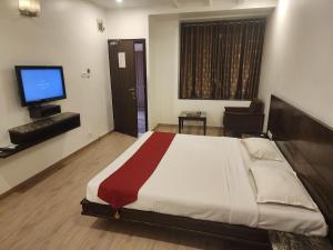 a bedroom with a large bed and a television at Hotel Ikon in Hubli