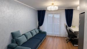 a living room with a blue couch and a desk at Spacious 3-Room Apartment - NEW Building in Bucharest