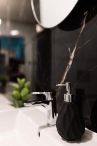 a black soap dispenser sitting on top of a bathroom sink at GOLDEN HAUS Opole - Black Velvet & Dark Elegance in Opole