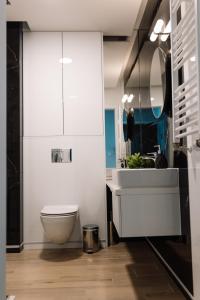 a bathroom with a white toilet and a sink at GOLDEN HAUS Opole - Black Velvet & Dark Elegance in Opole