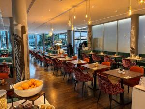 a restaurant with tables and chairs and a bowl of oranges at Windmill Frankfurt Niederrad in Frankfurt