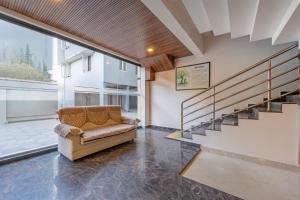 a living room with a couch and a staircase at Treebo Regalia, Near Medical College & Pattom in Trivandrum