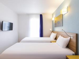 a hotel room with two beds and a window at Aparthotel Adagio Access La Défense - Place Charras in Courbevoie +28 photos