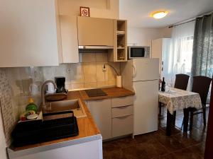 a small kitchen with a white refrigerator and a table at Apartments Prendivoj in Malinska