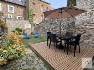 a table and chairs with an umbrella on a wooden deck at La Maison de Pêcheurs in Cancale
