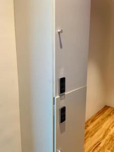 a white refrigerator in a room with a wooden floor at TRIVPODS Capsule Hotel in Trivandrum