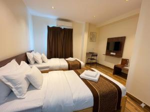 a hotel room with two beds and a television at De Classico Hotel - HBR Layout in Bangalore