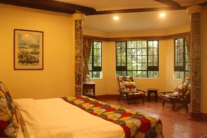 ein Schlafzimmer mit Bett, Stühlen und Fenstern in der Unterkunft Marangu Hotel in Marangu + 18 Fotos