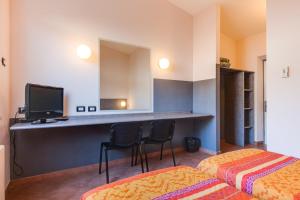 a hotel room with two beds and a desk with a television at Autohotel Venezia in Mirano