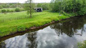 a view of a river with a hut in the background at Riverside weekend cabin in Upesciems