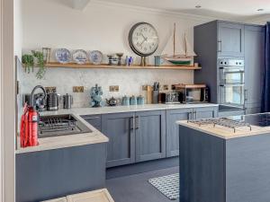 a kitchen with blue cabinets and a clock on the wall at Nautilus Cottage in Cellardyke