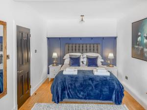 a bedroom with a large blue bed with two lamps at Nautilus Cottage in Cellardyke