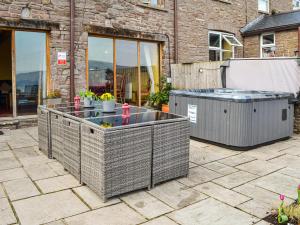 a patio with a hot tub and two trash at Peacock Cottage - Uk36422 in Talybont