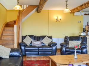 a living room with two leather couches and a table at Peacock Cottage - Uk36422 in Talybont +7 photos