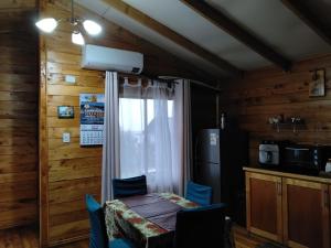 a dining room with a table and chairs and a window at Cabañas miranda in Quellón +4 photos