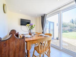 a dining room with a wooden table and a sliding glass door at Rathlin Cottage in Cambridge