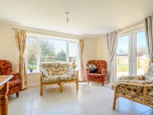a living room with couches and chairs and windows at Rathlin Cottage in Cambridge