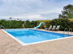 a swimming pool with a slide and two chairs at Bournestream Cottage in Withycombe