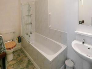 a bathroom with a tub and a toilet and a sink at Bournestream Cottage in Withycombe