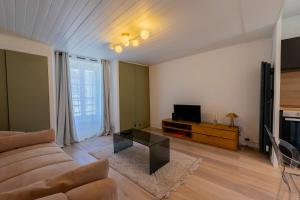 a living room with a couch and a television at l'Onyx in La Rochelle