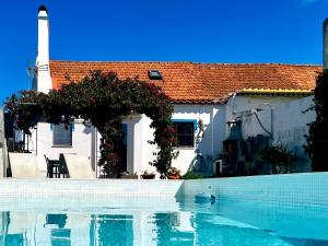 a house with a swimming pool in front of a house at BuganVilla in Santiago do Cacém
