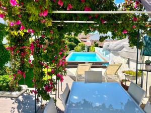 a patio with a blue table and flowers and a swimming pool at BuganVilla in Santiago do Cacém