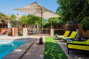a patio with an umbrella and chairs and a pool at El Grifo Casa De Campo Con Piscina in Carmona