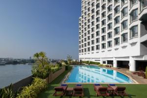 a hotel with a swimming pool next to a building at Montien Riverside Hotel Bangkok in Bangkok