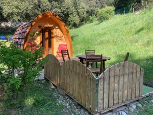 a wooden fence with a table and a tent at Hébergements Insolites Camping la Pinède des Mées in Les Mées