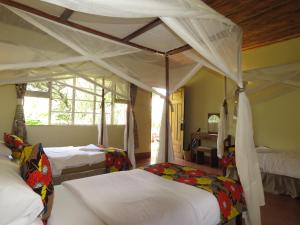 ein Schlafzimmer mit zwei Betten und einem Himmelbett in der Unterkunft Marangu Hotel in Marangu
