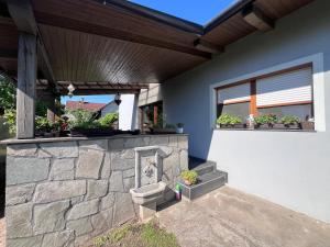 a house with a stone retaining wall with potted plants at Vadkörte Balaton Apartman in Balatonfůzfő
