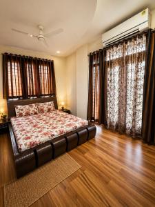 a bedroom with a bed and wooden floors and windows at Urbana Luxury AC Duplex Bungalow with Pergola Terrace in Nagpur