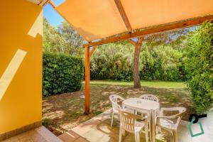 a patio with a table and chairs under an orange umbrella at Hotiday Marina di Cecina in La Cinquantina