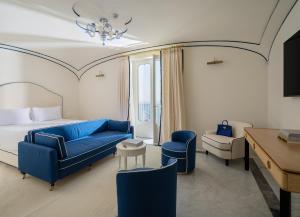 a hotel room with a blue couch and a bed at Hotel du Tasso Sorrento in Sorrento