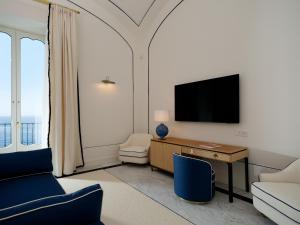 a living room with a tv and a desk and chairs at Hotel du Tasso Sorrento in Sorrento +11 photos