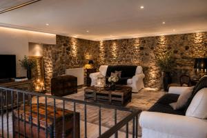 a living room with stone walls and white furniture at La Maison De Marthe in Malleval