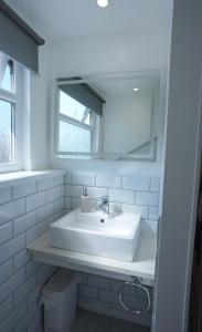 a white bathroom with a sink and a mirror at Steps to the Sand in Melcombe Regis