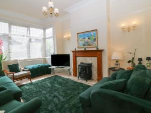 a living room with a green couch and a fireplace at Gwynfa in Colwyn Bay