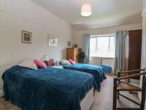 a bedroom with two beds with blue sheets and pink pillows at Gwynfa in Colwyn Bay